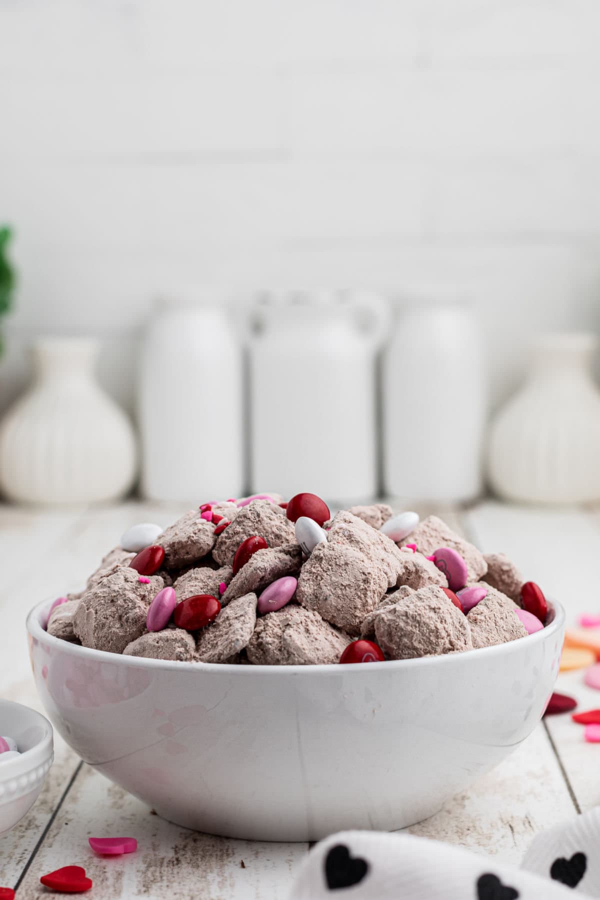 A bowl of red velvet Muddy Buddies on a white table.