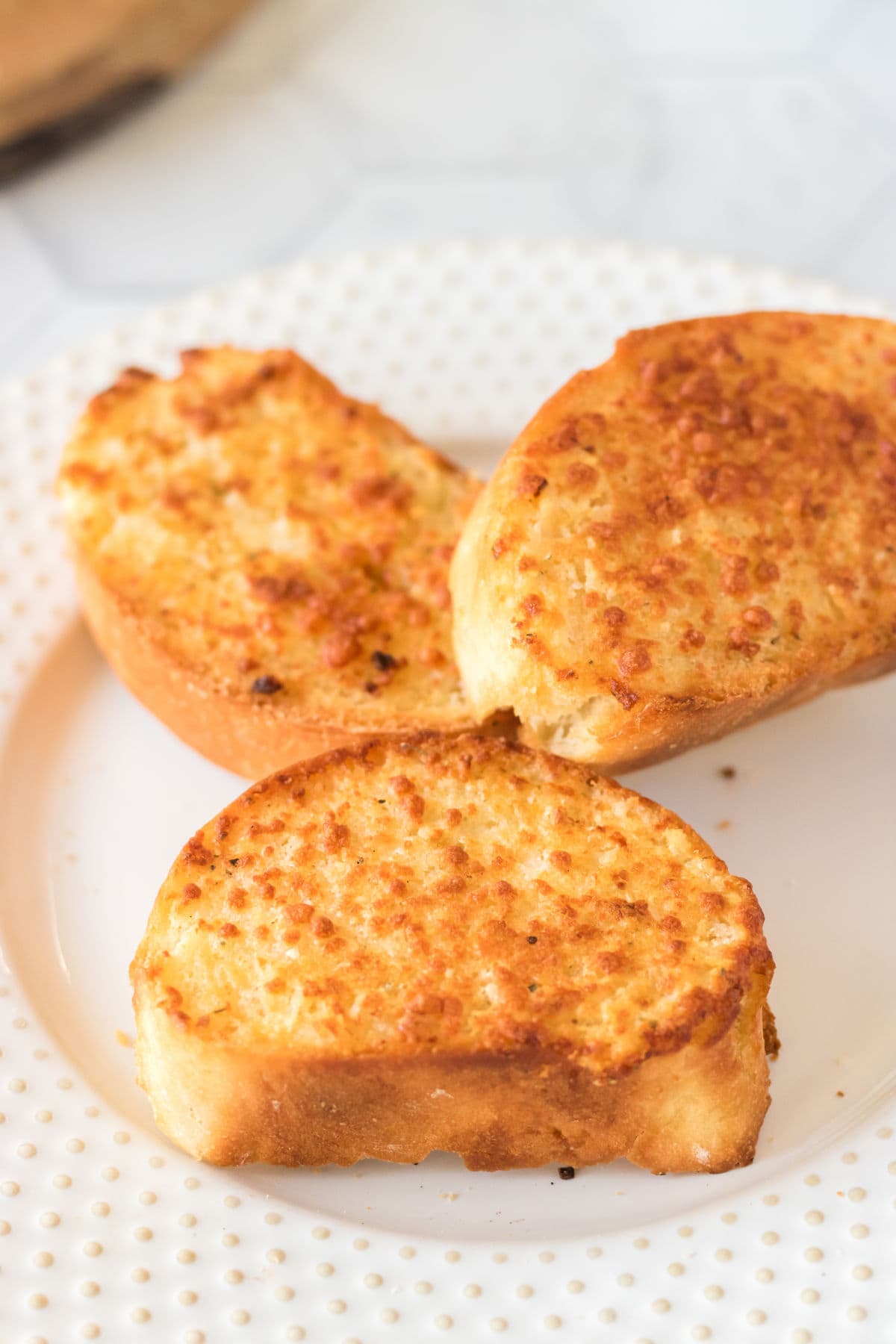 A white plate with garlic bread on it.