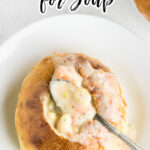 Overhead view of a bread bowl filled with soup with text overlay for Pinterest.