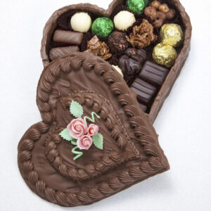 A chocolate heart shaped box with chocolates inside is on a white background.
