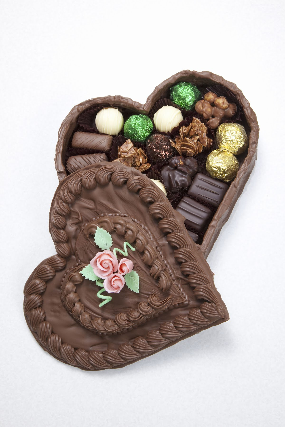 A chocolate box with w candy rose on the cover is filled with chocolate candies.