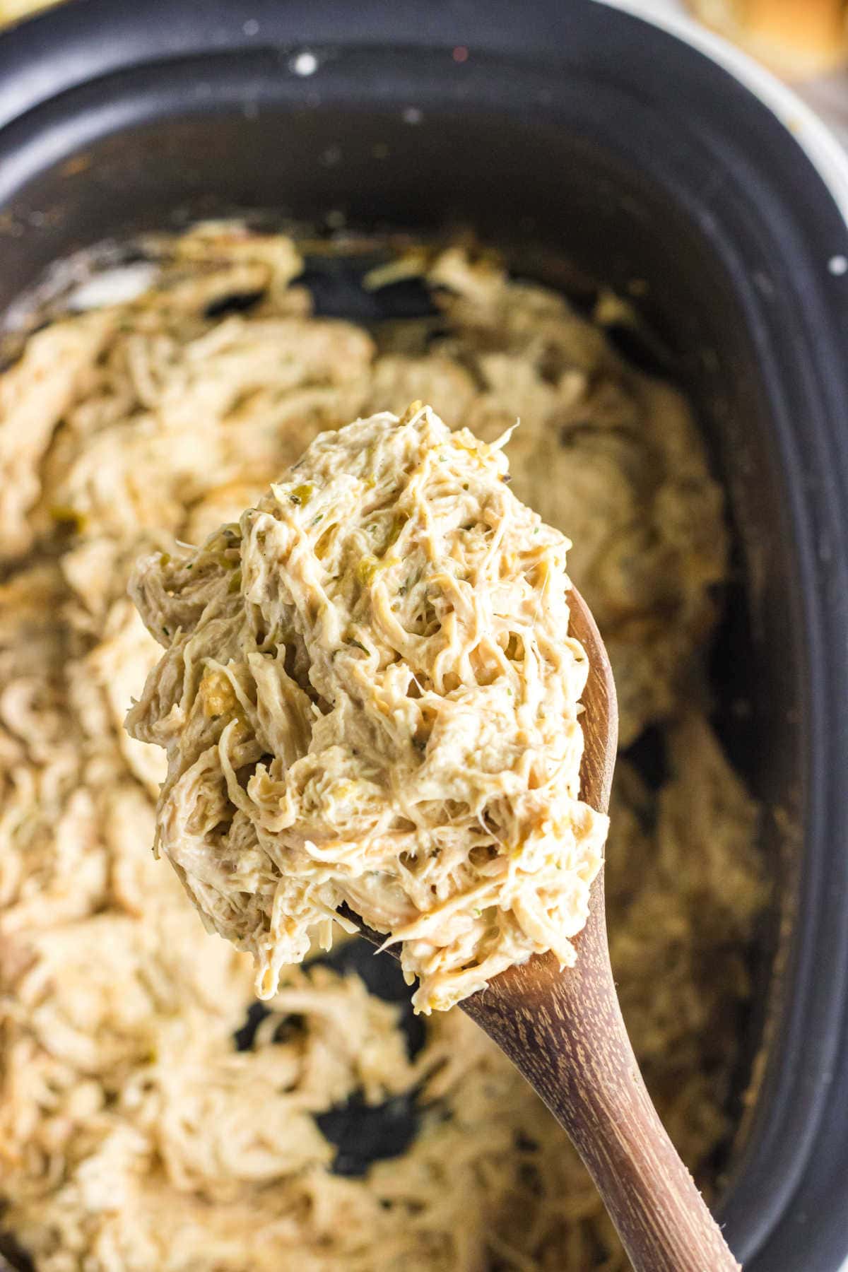 A spoonful of chicken being lifted from the slow cooker.