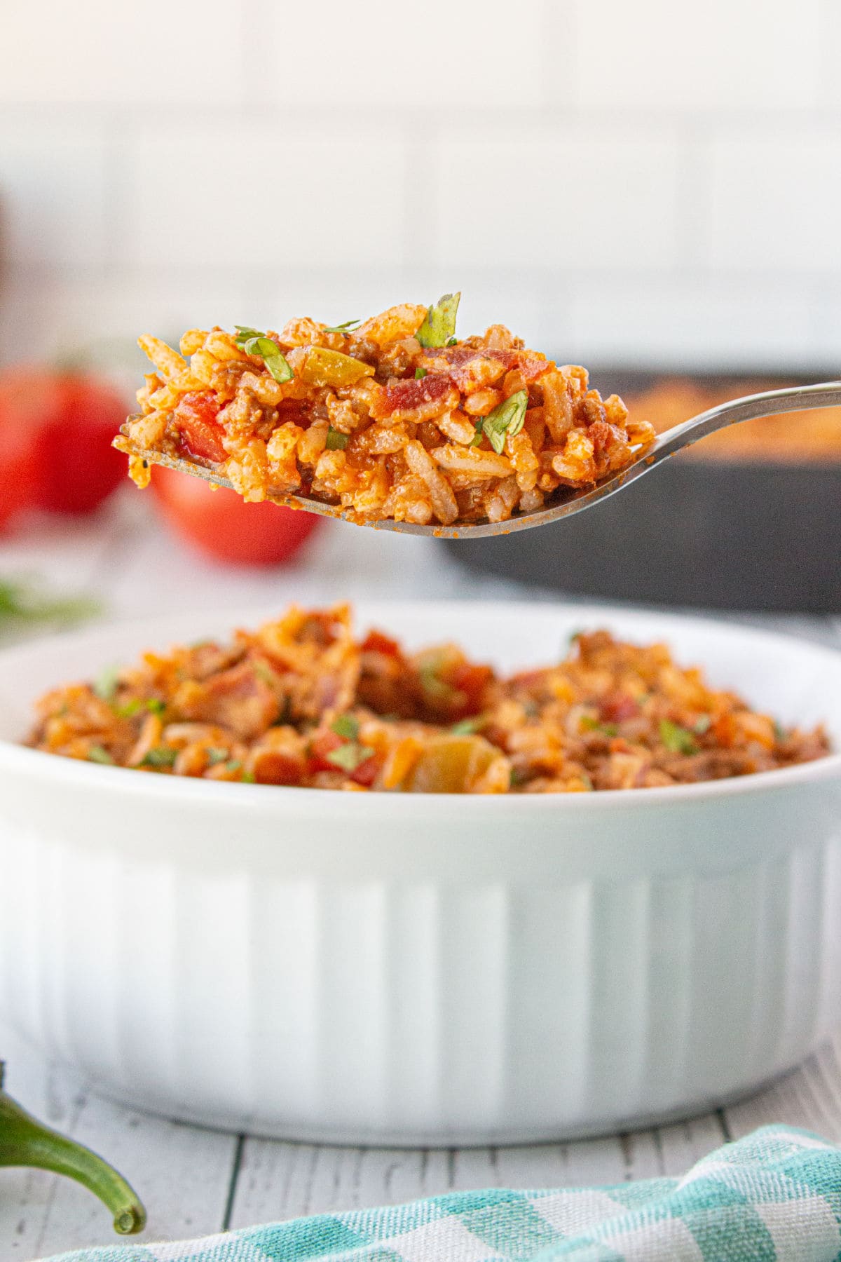 A spoonful of Spanish rice being lifted from a bowl.