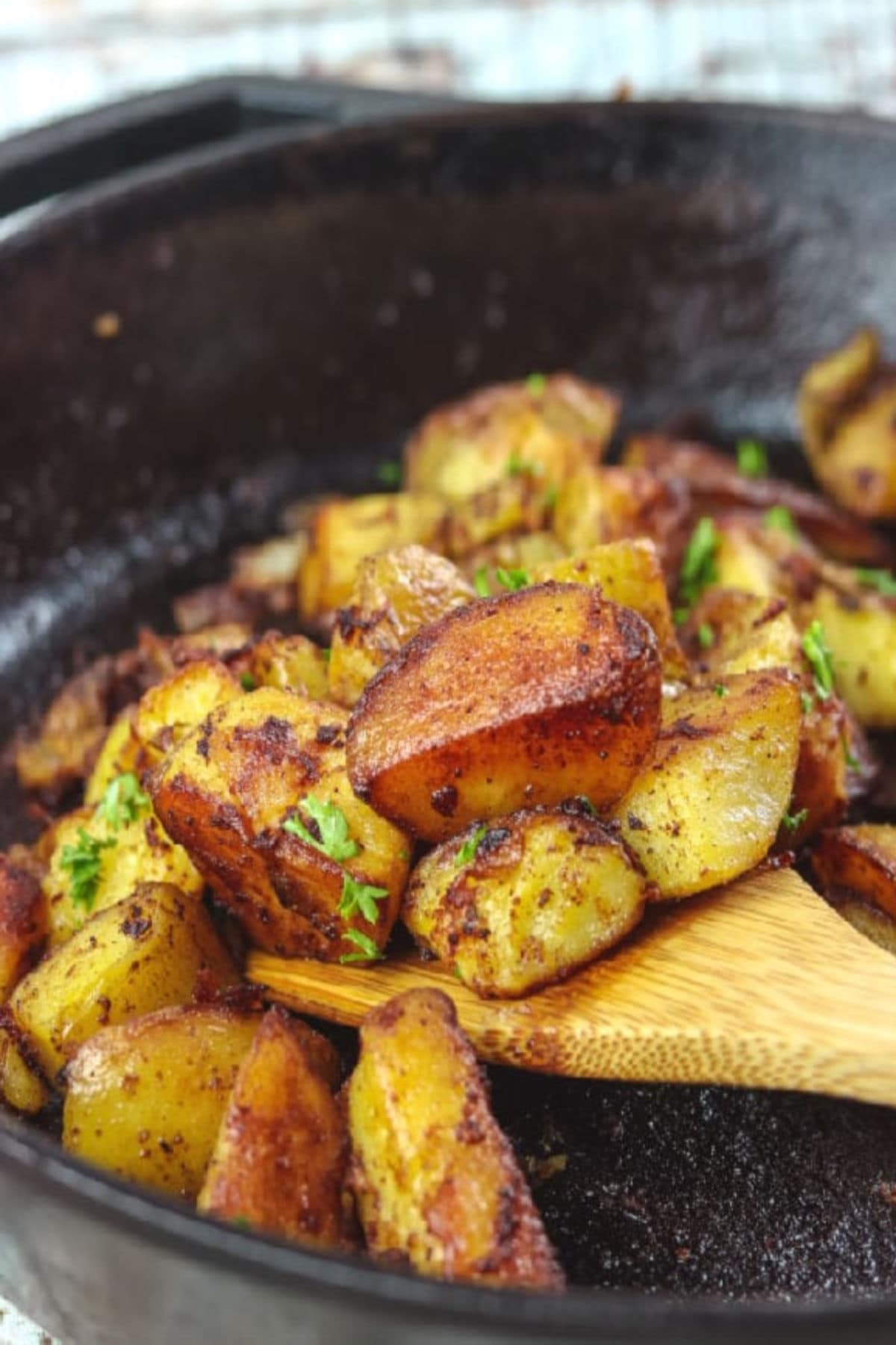 Closeup of golden brown fried potatoes in an iron skillet.