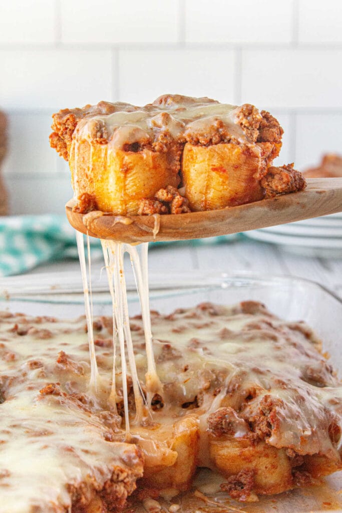 A serving of casserole being removed from the dish with strands of melty cheese.