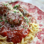 Closeup of meatballs on top of a pile of spaghetti.