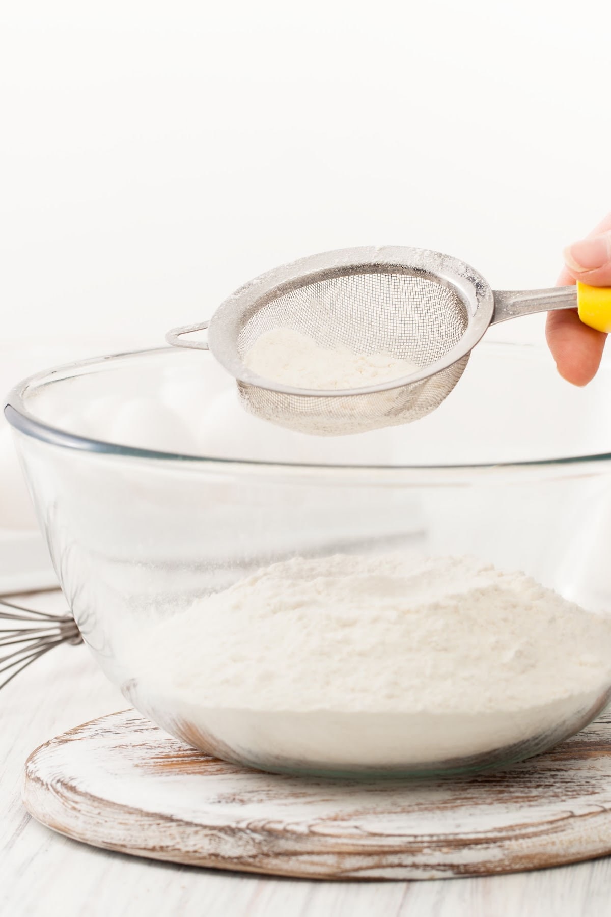 Someone sifting flour into a bowl.