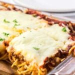 A closeup of a serving of pasta being lifted from a casserole dish with a text overlay for Pinterest.