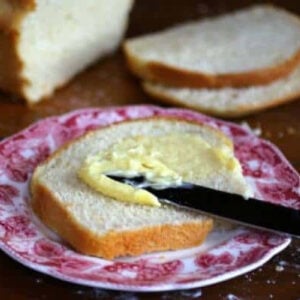 A slice of white bread being buttered.