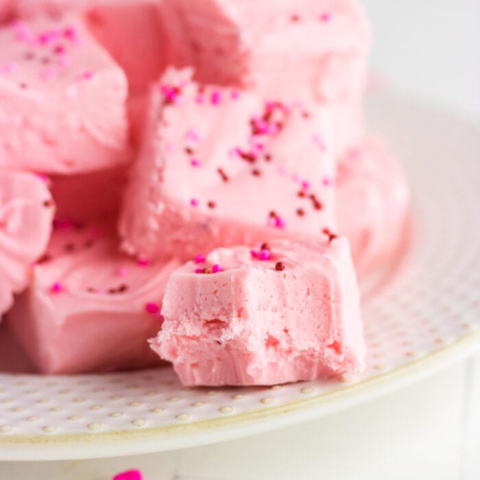 Closeup of pink strawberry fudge with a bite out of it showing the creamy texture.