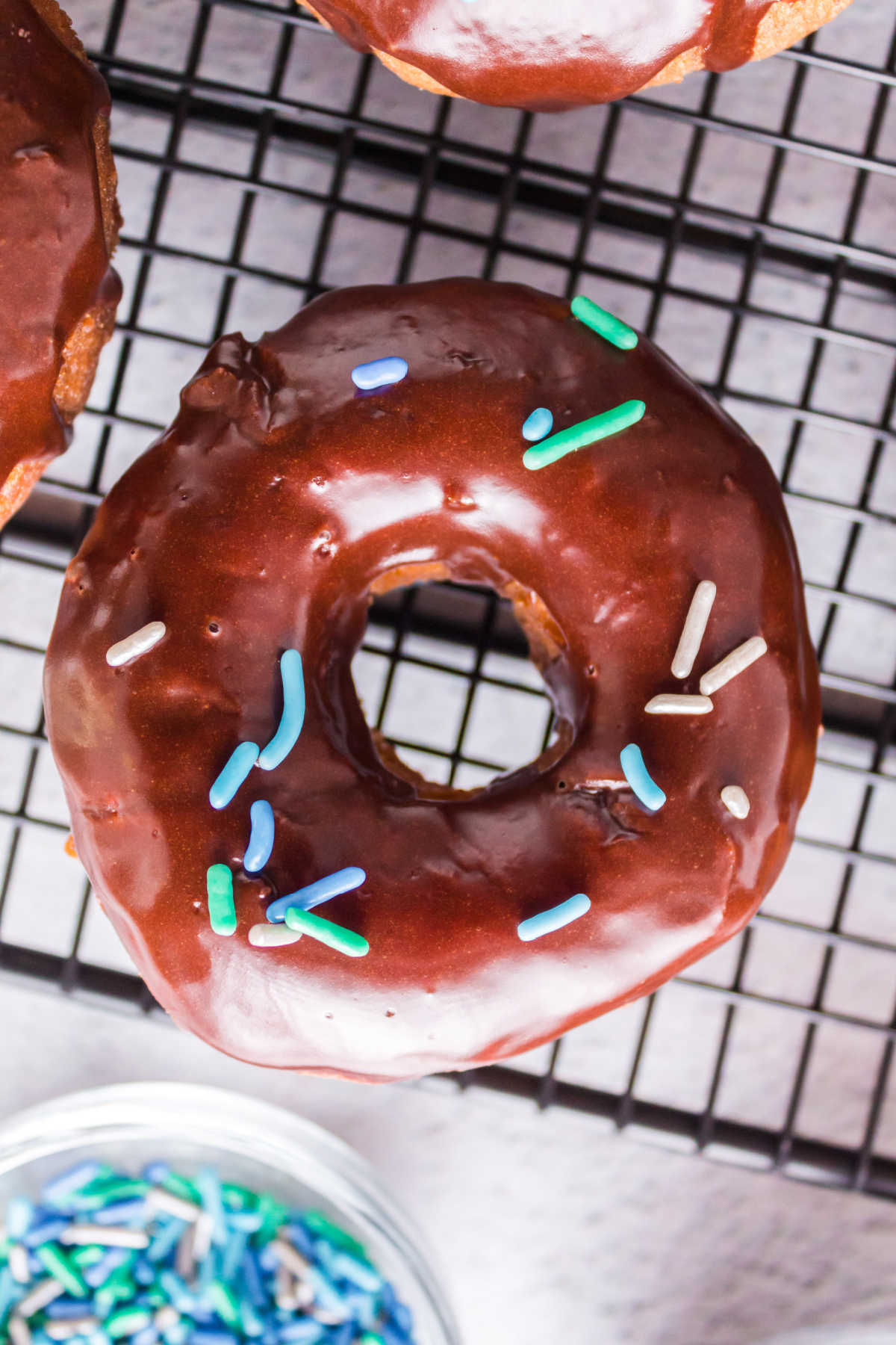 Overhead view of a chocolate frosted donut on a wire rack.