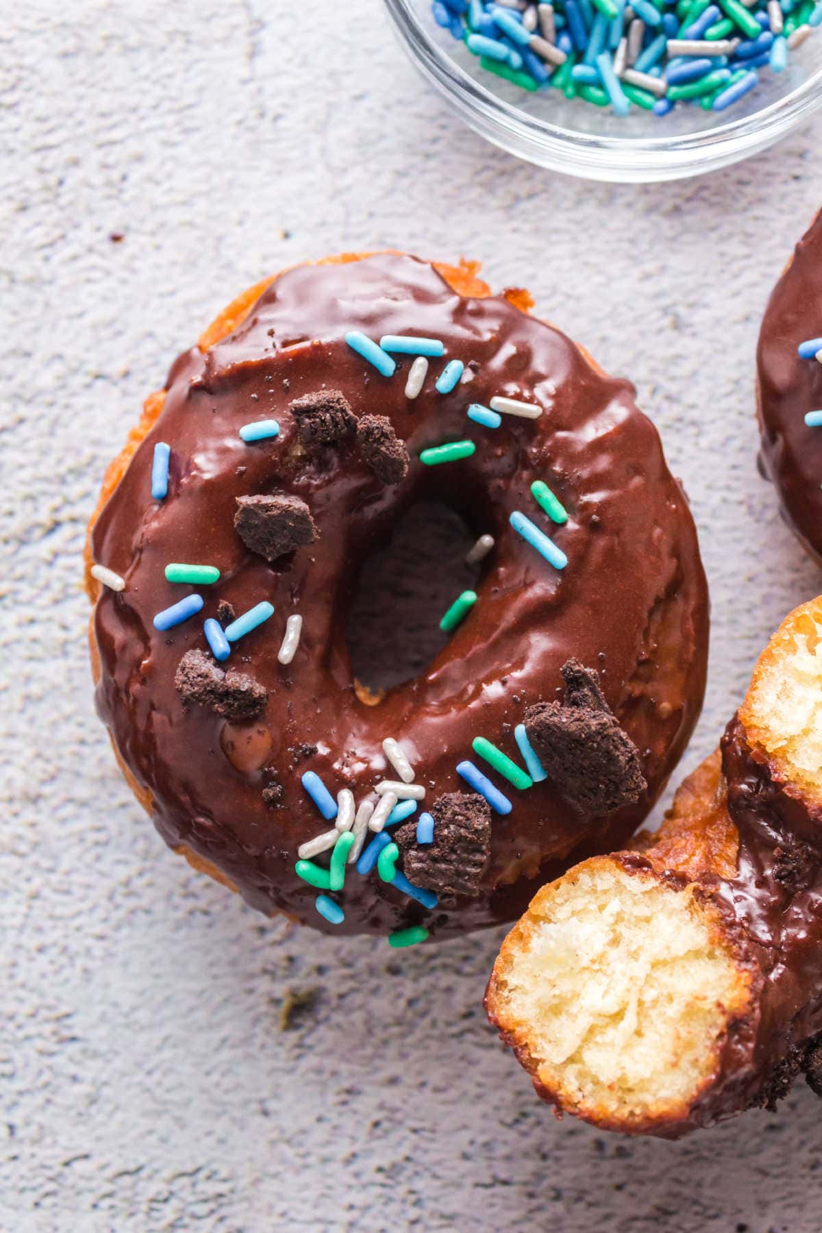 Overhead view of chocolate frosted donuts with one cut in half to show the inside texture.