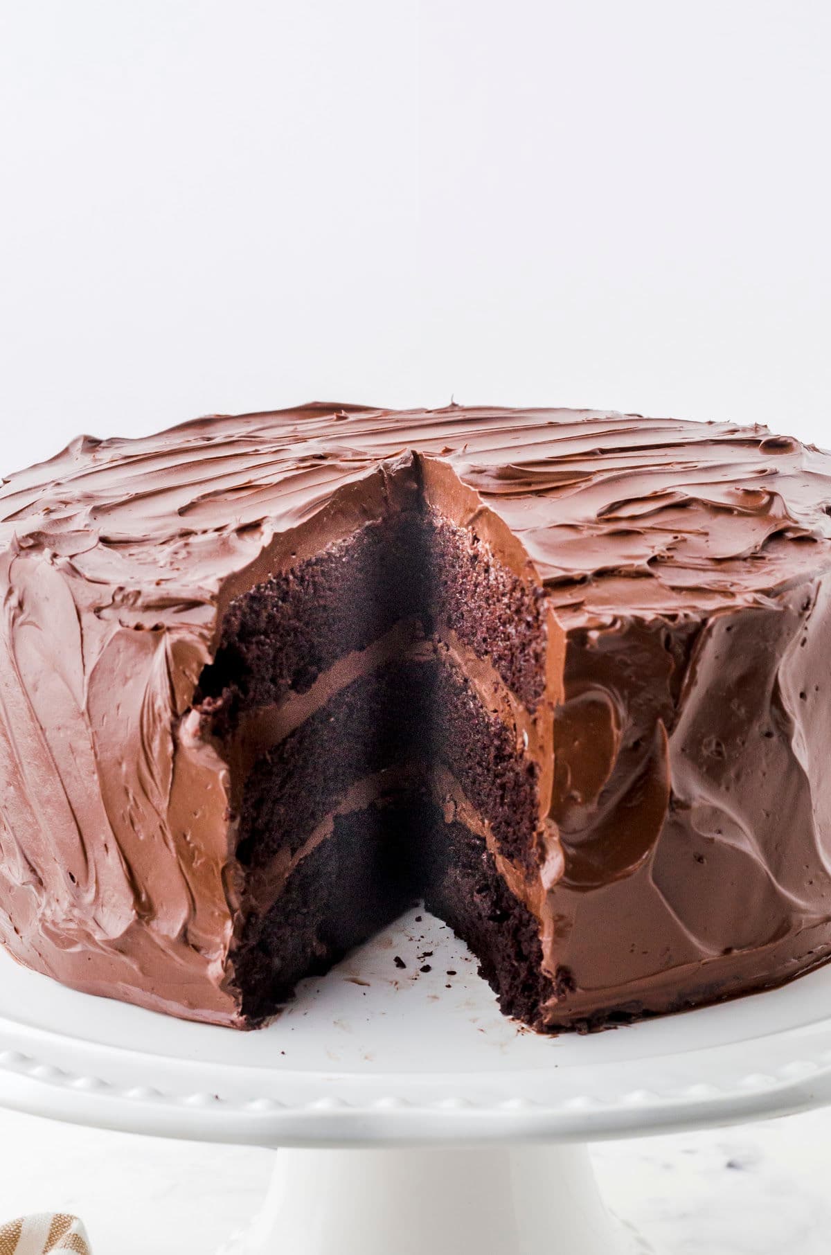 A chocolate layer cake with a slice removed to show the cake layers and filling.