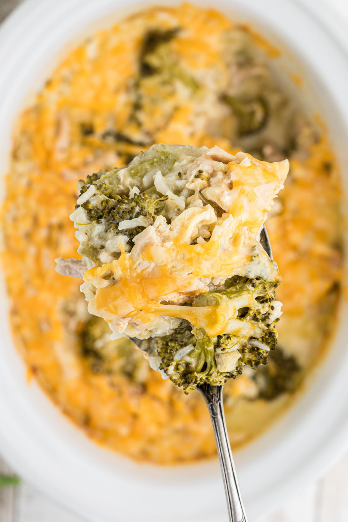 A serving of chicken and broccoli being removed from the slow cooker.