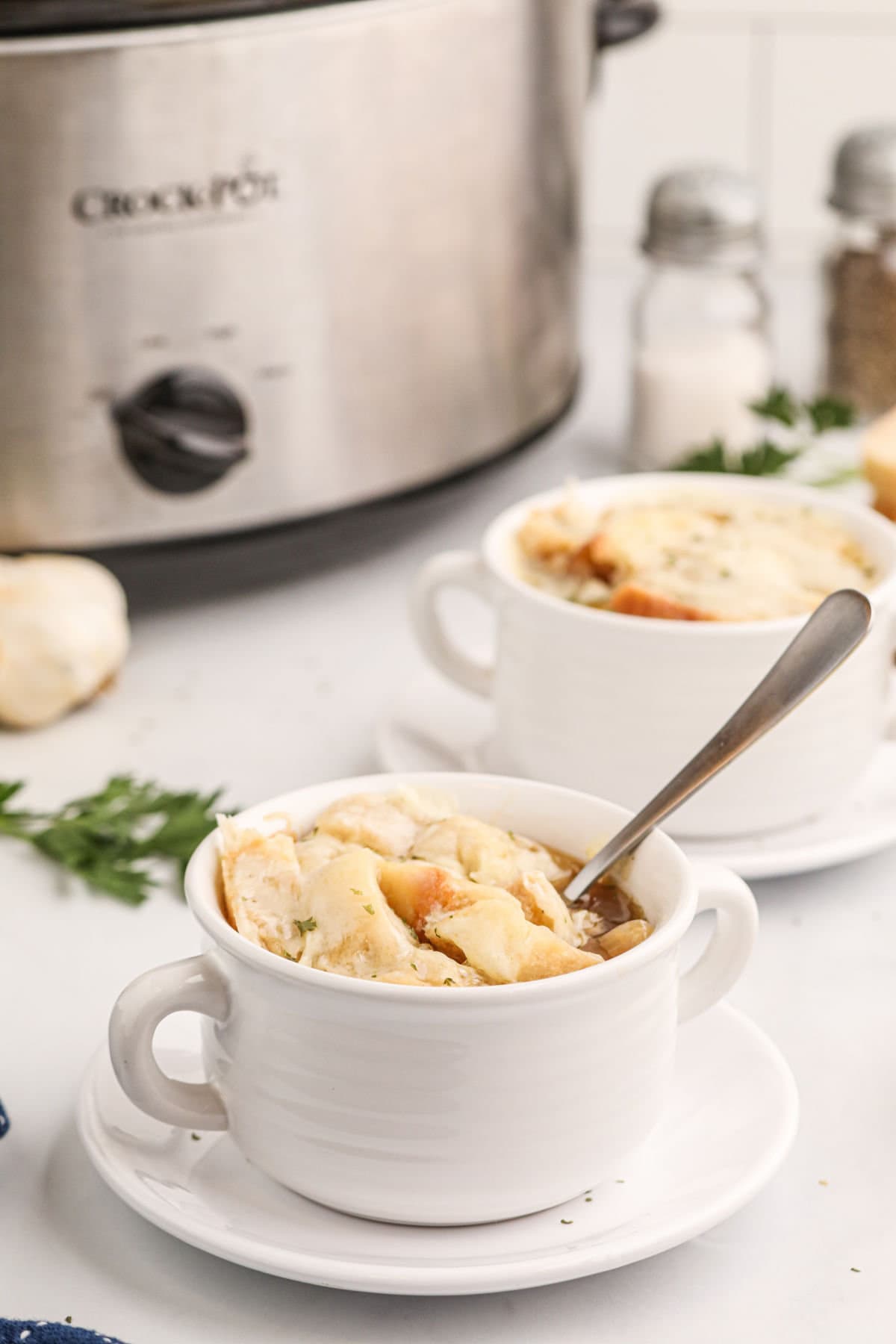 Two bowls of French onion soup on a table.