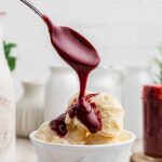 Red velvet hot fudge sauce being spooned over ice cream.