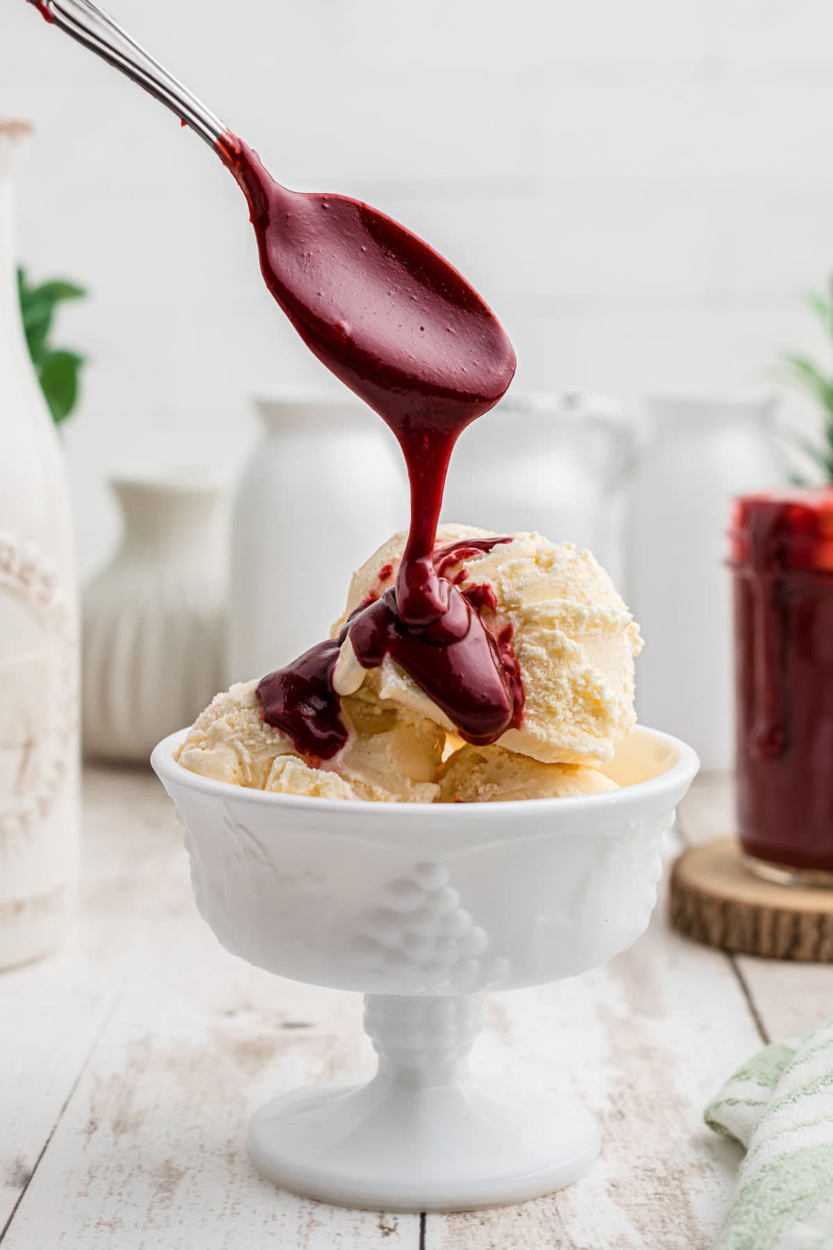 Red velvet hot fudge sauce being spooned on vanilla ice cream.