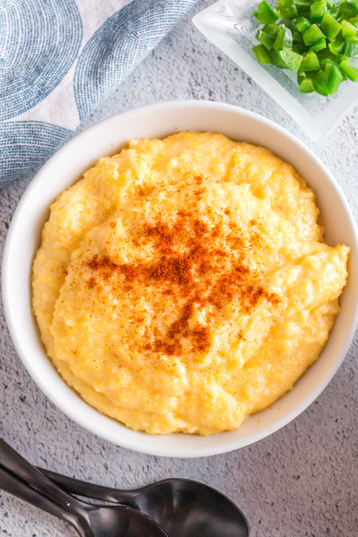 Grits being garnished with smoked paprika and chopped jalapenos.