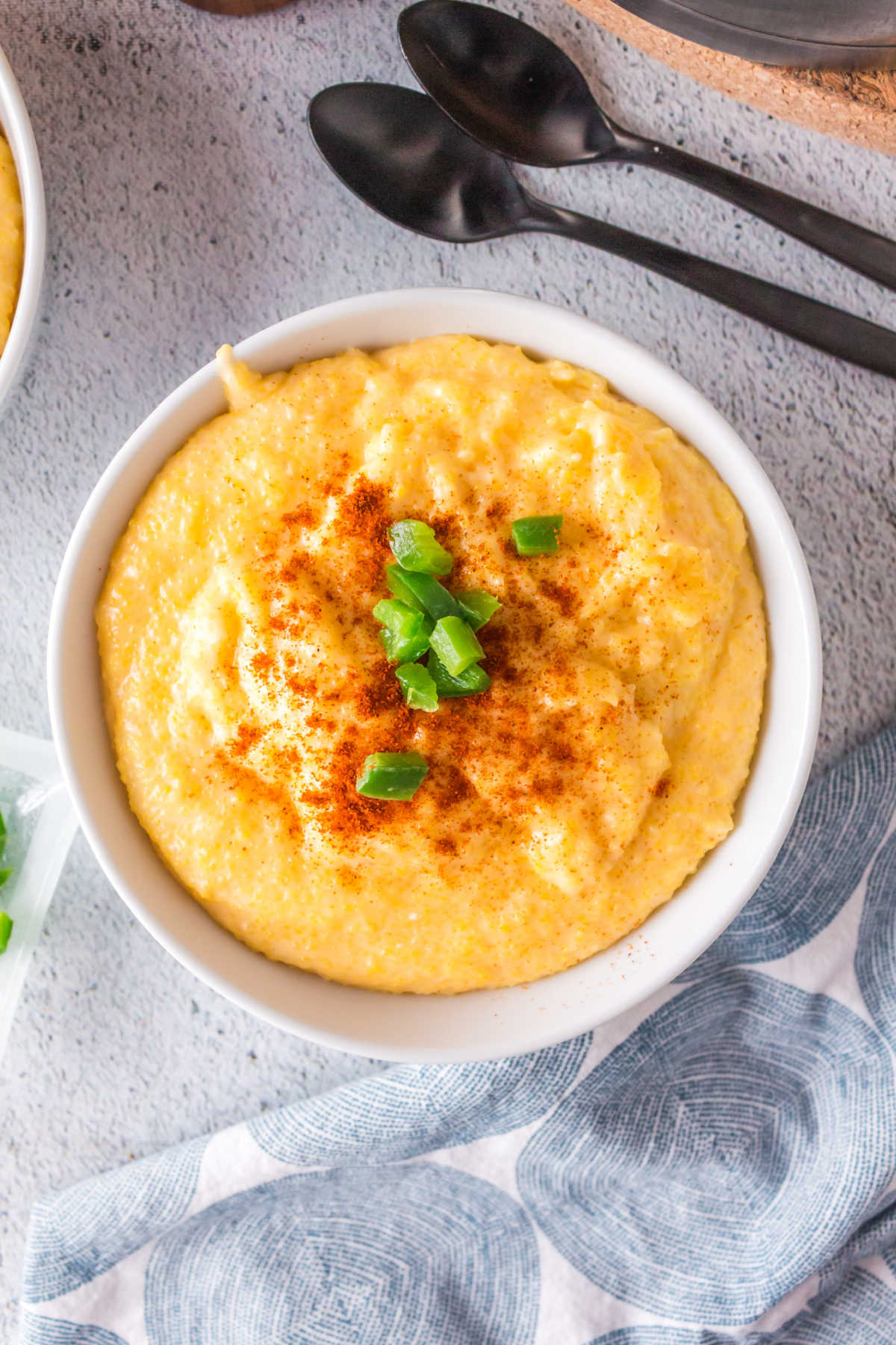 Overhead view of a bowl of cheesy grits with chopped jalapenos on top.