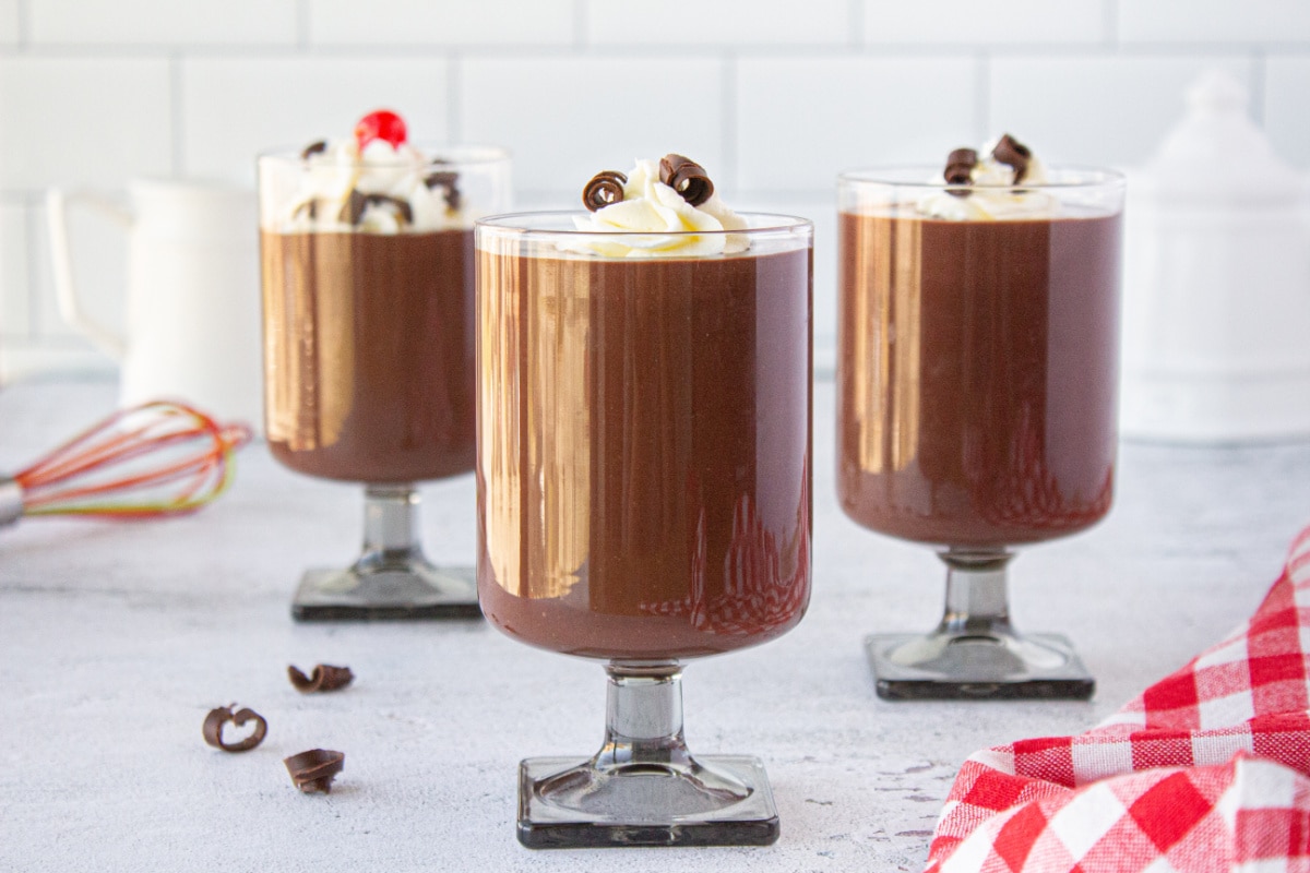 Three glasses filled with pudding on a table.