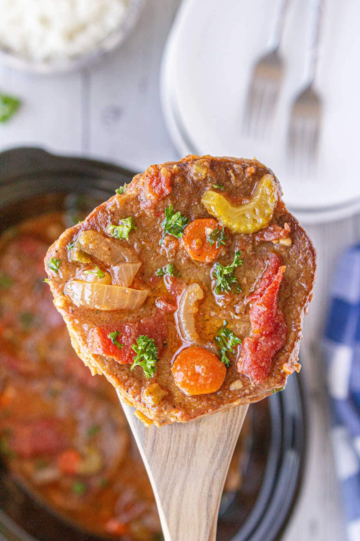 A serving of swiss steak being removed from the slow cooker.