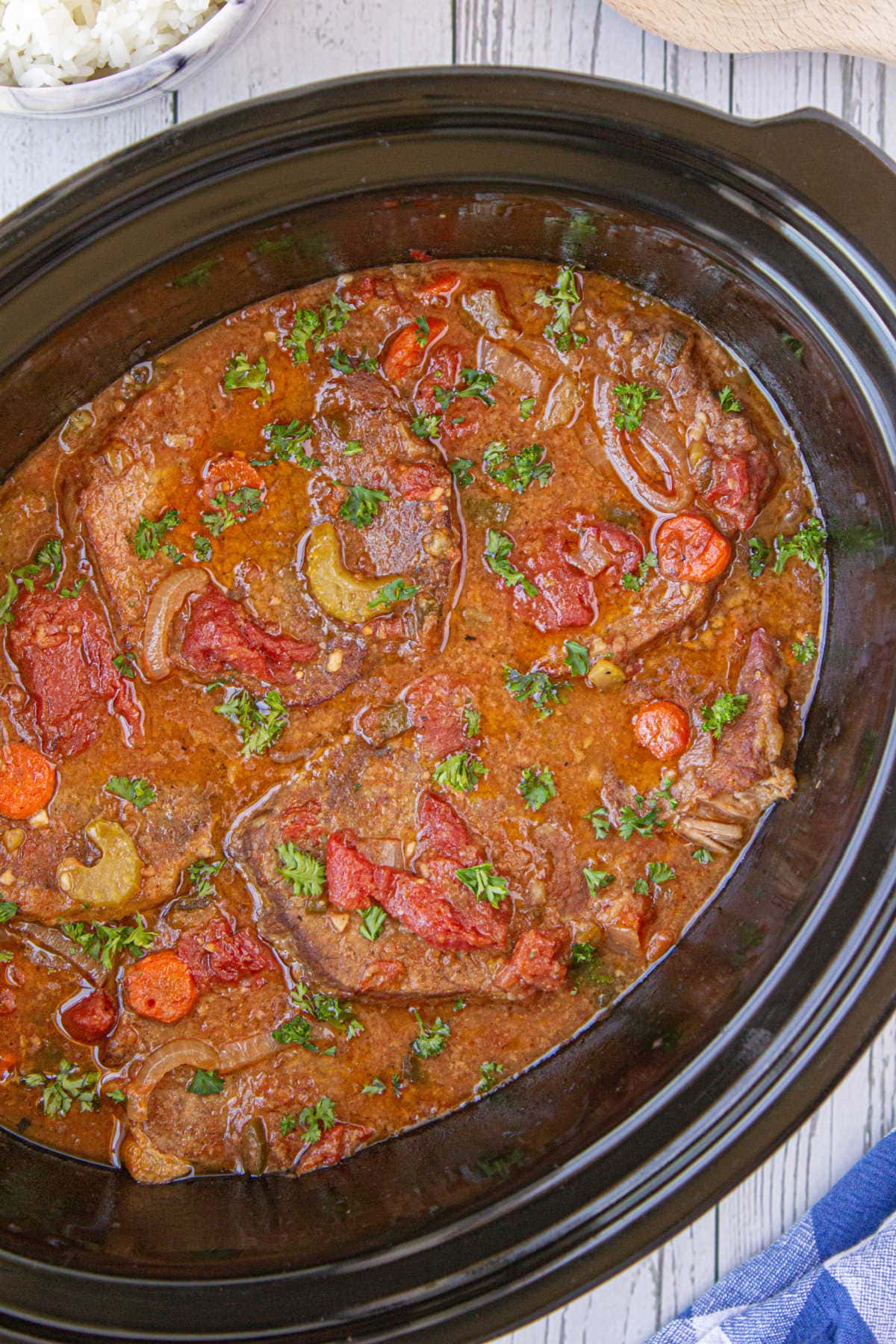 A crockpot filled with steak and vegetables in a tomato sauce.