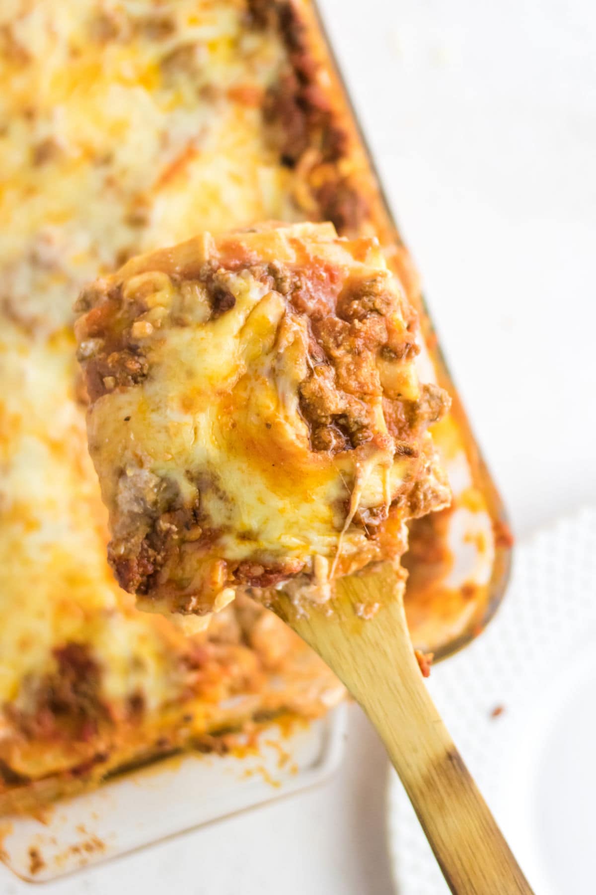 A serving of lasagna on a wooden spatula.