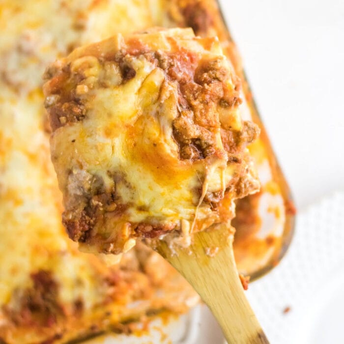 A serving of lasagna being taken from the casserole dish.