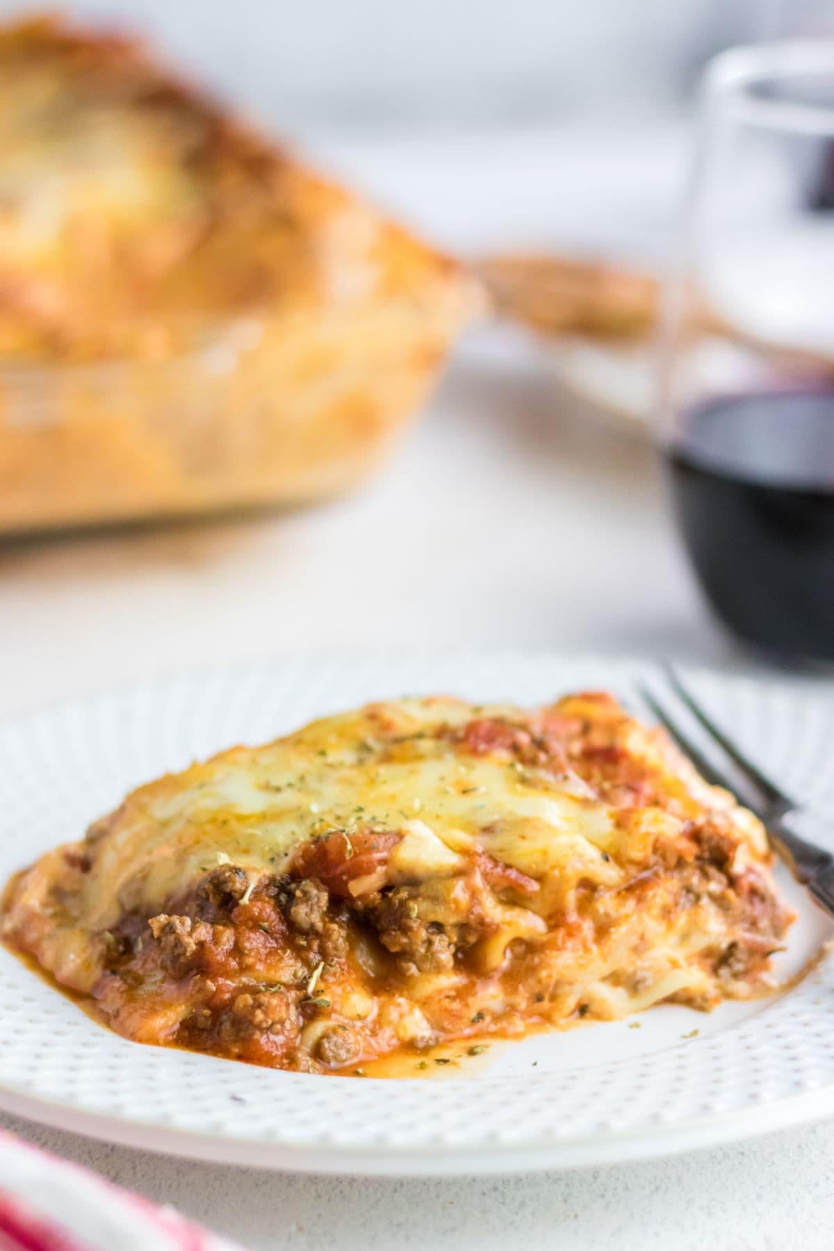 A serving of lasagna on a dinner plate.