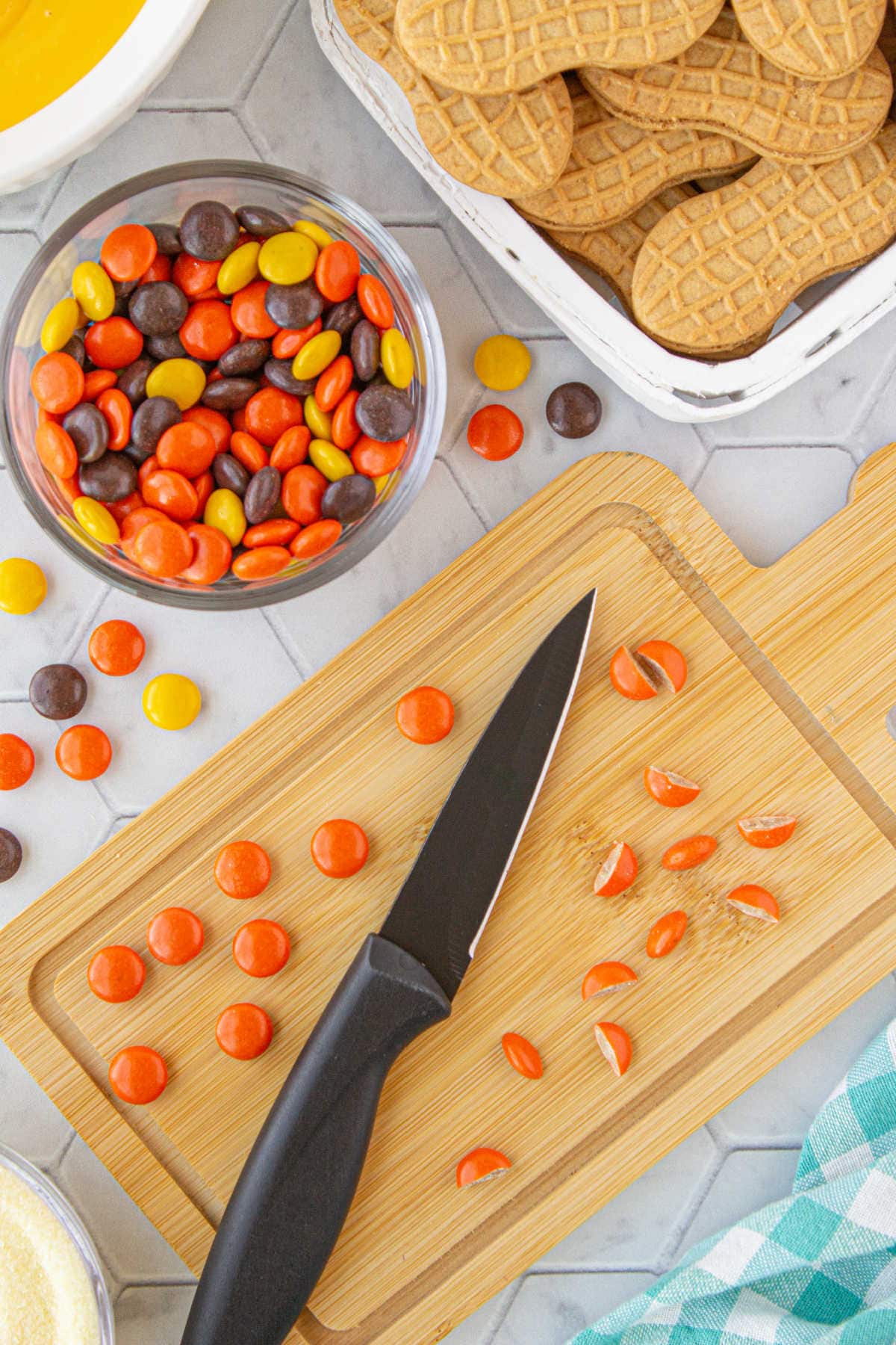 Orange Reese's Pieces cut in half on a cutting board.