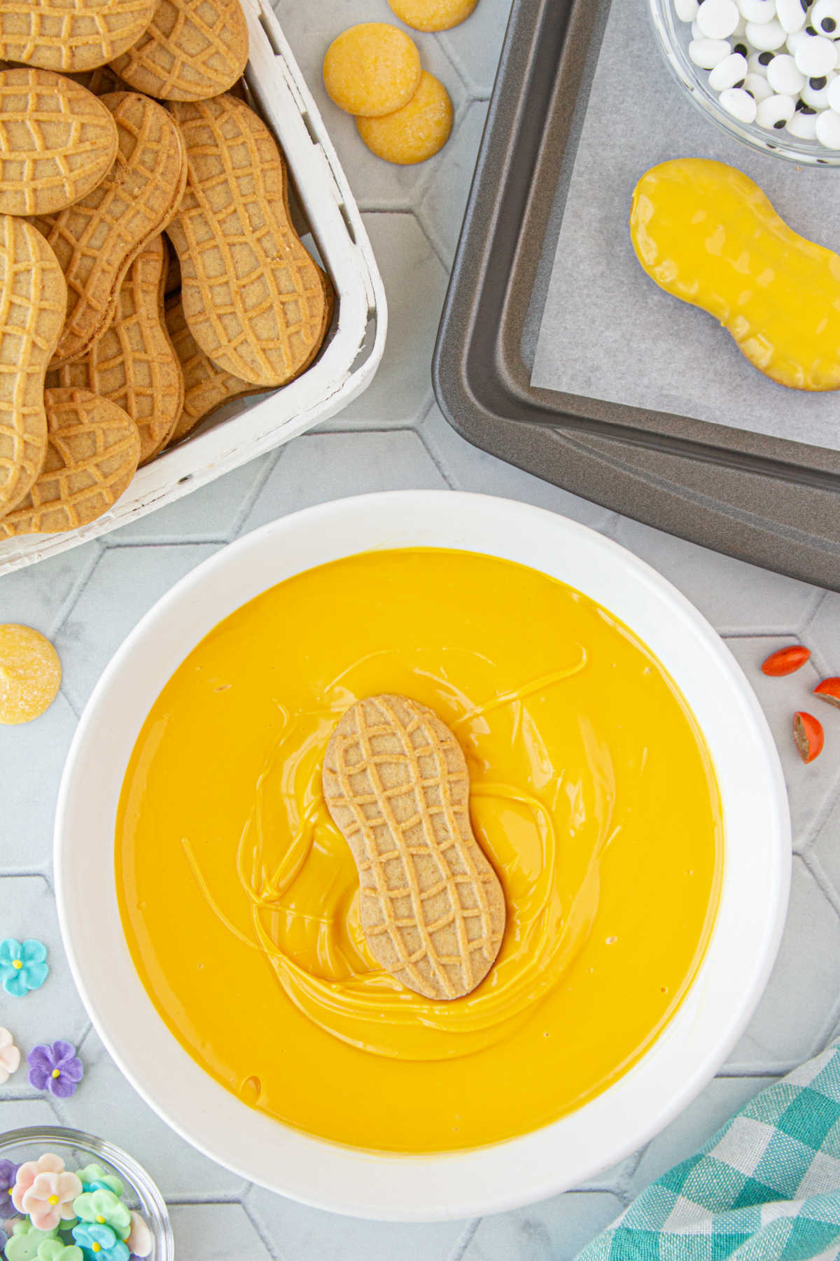 A cookie being dipped in the melted yellow candy melts.