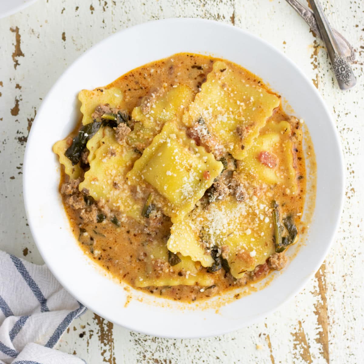 Overhead view of ravioli soup in a white bowl.