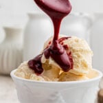 A spoon pouring red velvet hot fudge sauce on ice cream with a text overlay for Pinterest.