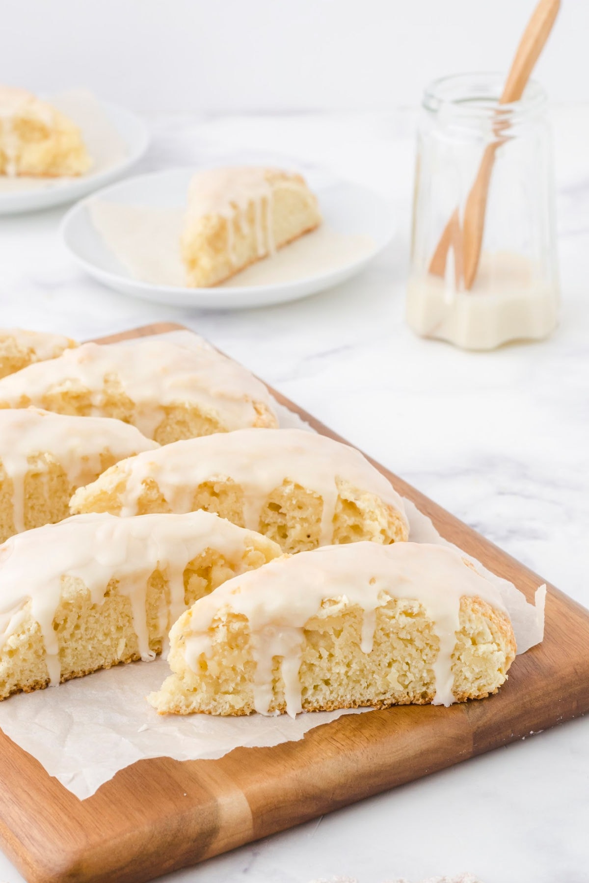 Vanilla scones with glaze dripping down the sides.