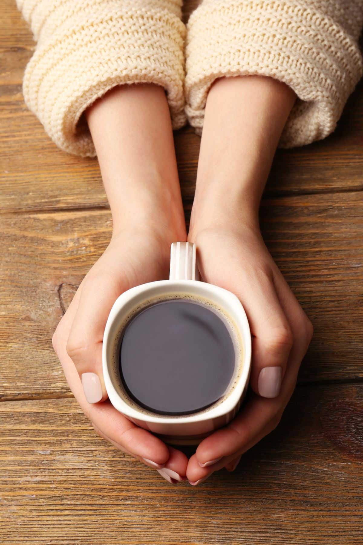 Hands holding a coffee cup.