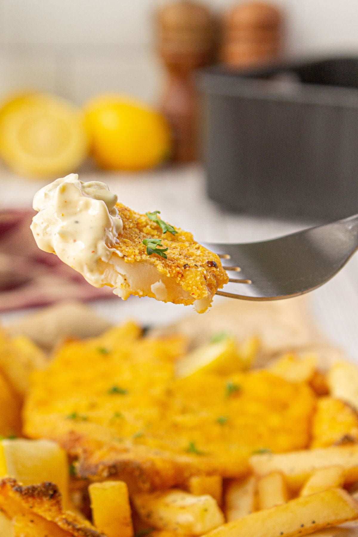 A forkful of catfish with tartar sauce on it.