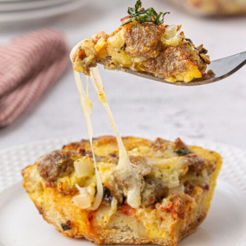 Side view of a serving of casserole on a fork with gooey cheese.