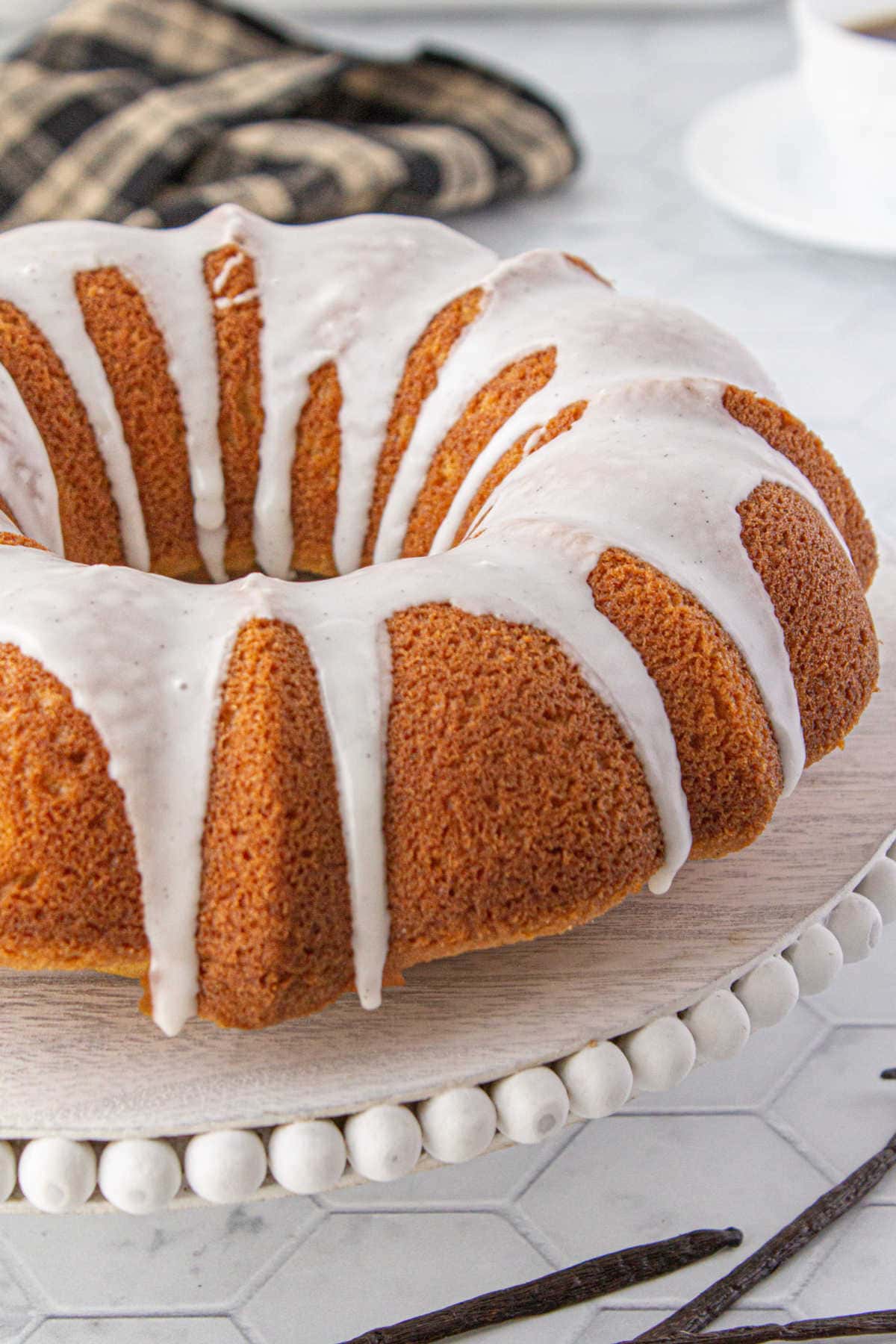 A bundt cake with white glaze on a cake plate.