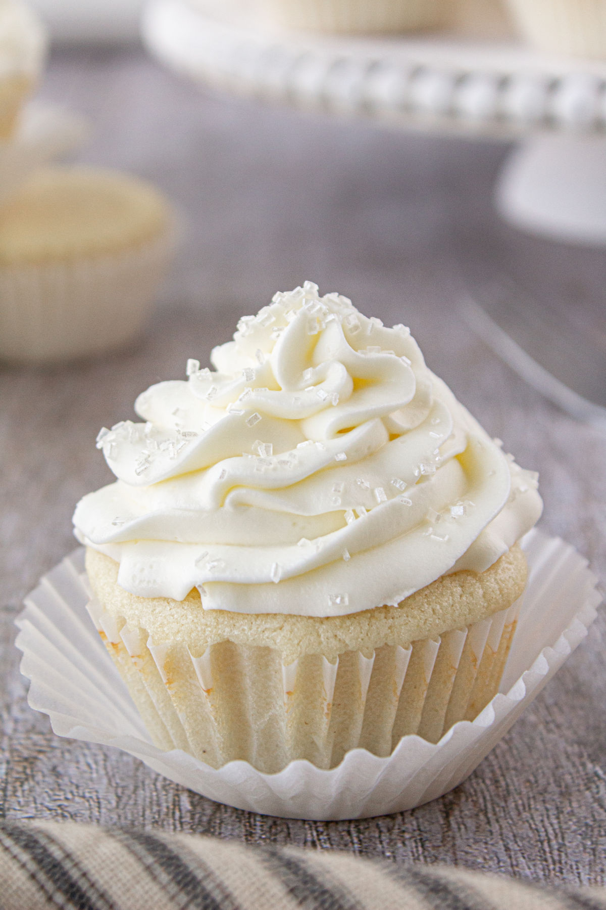 A single white cupcake with creamy white frosting on a table.