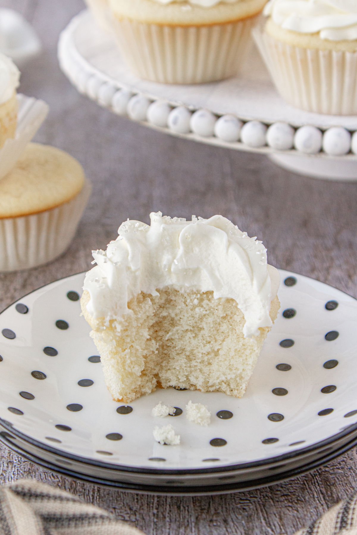 A white cupcake with a bite removed showing the interior.