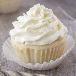Closeup of a single white cupcake showing the texture of the creamy frosting.