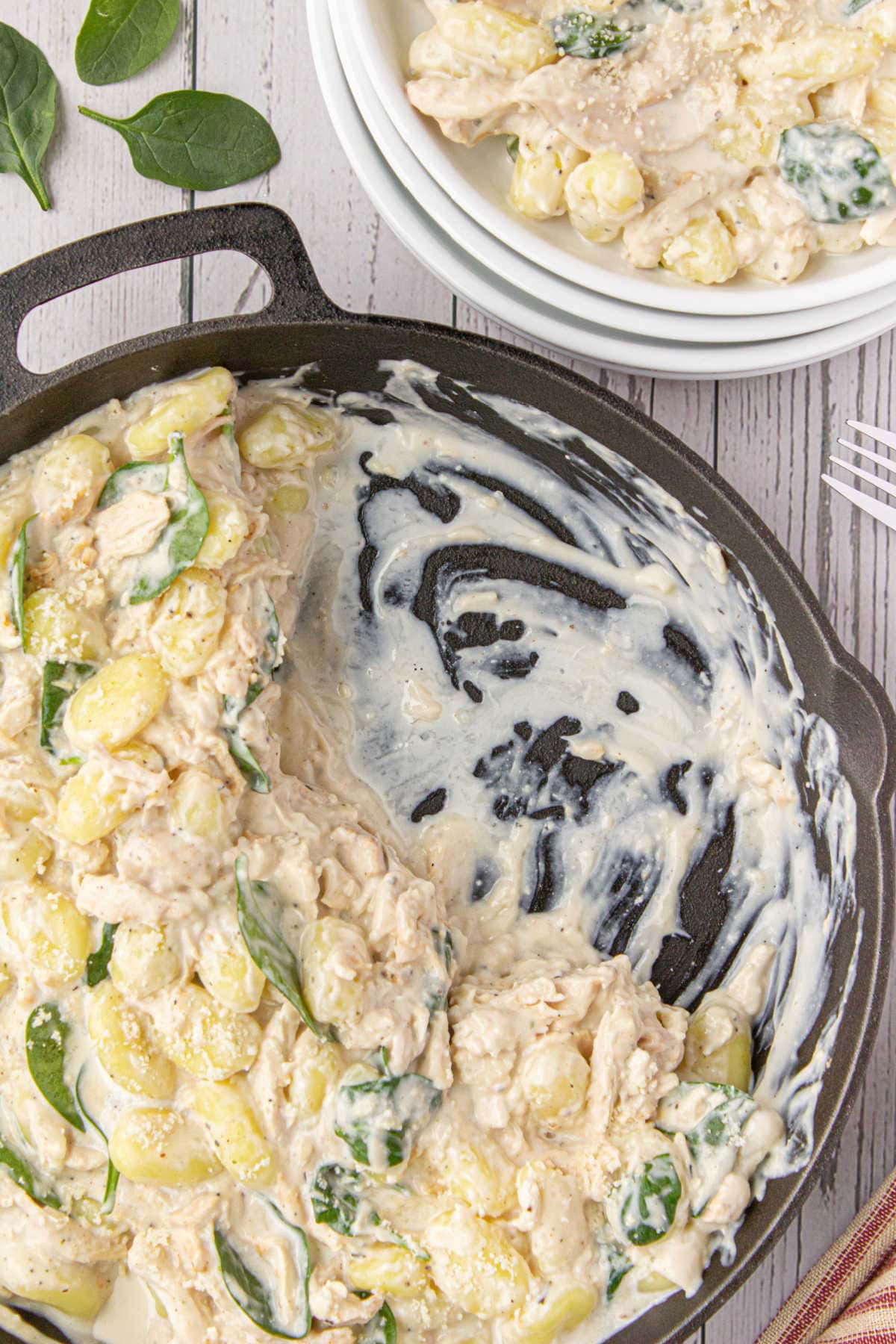 Overhead view of a pan of creamy gnocchi with a serving removed.