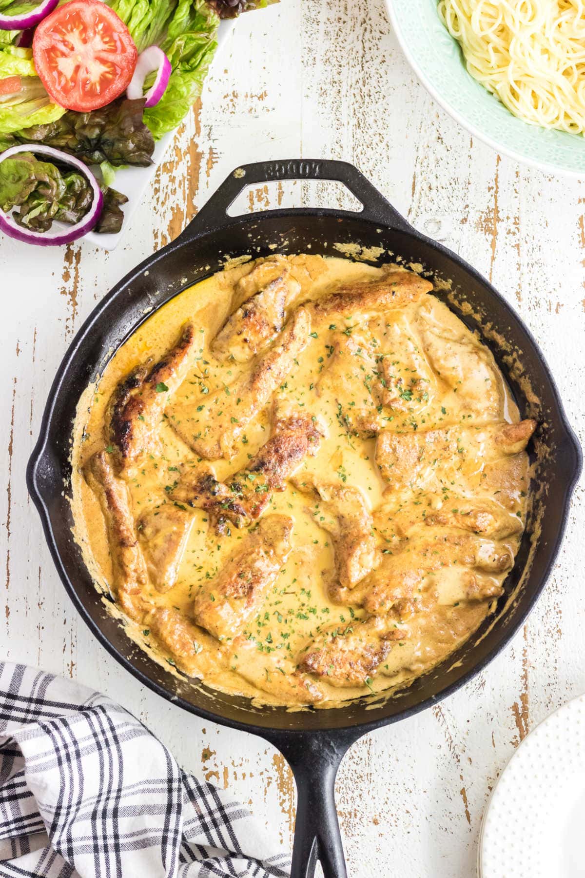 Overhead view of chicken in a skillet with a title text overlay.