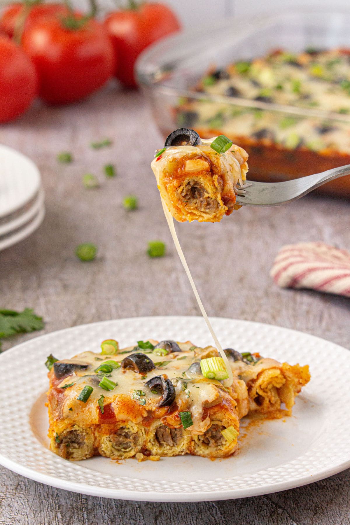 A plate with the casserole on it and a bite being removed with a fork.