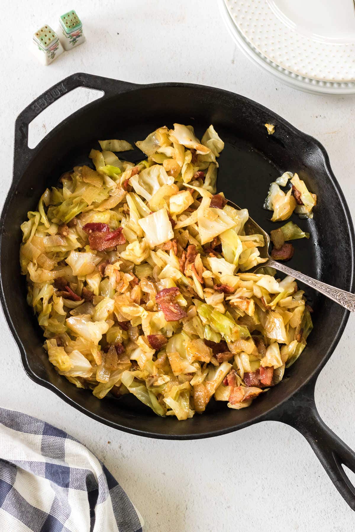 Overhead view of cabbage and bacon in an iron skillet.