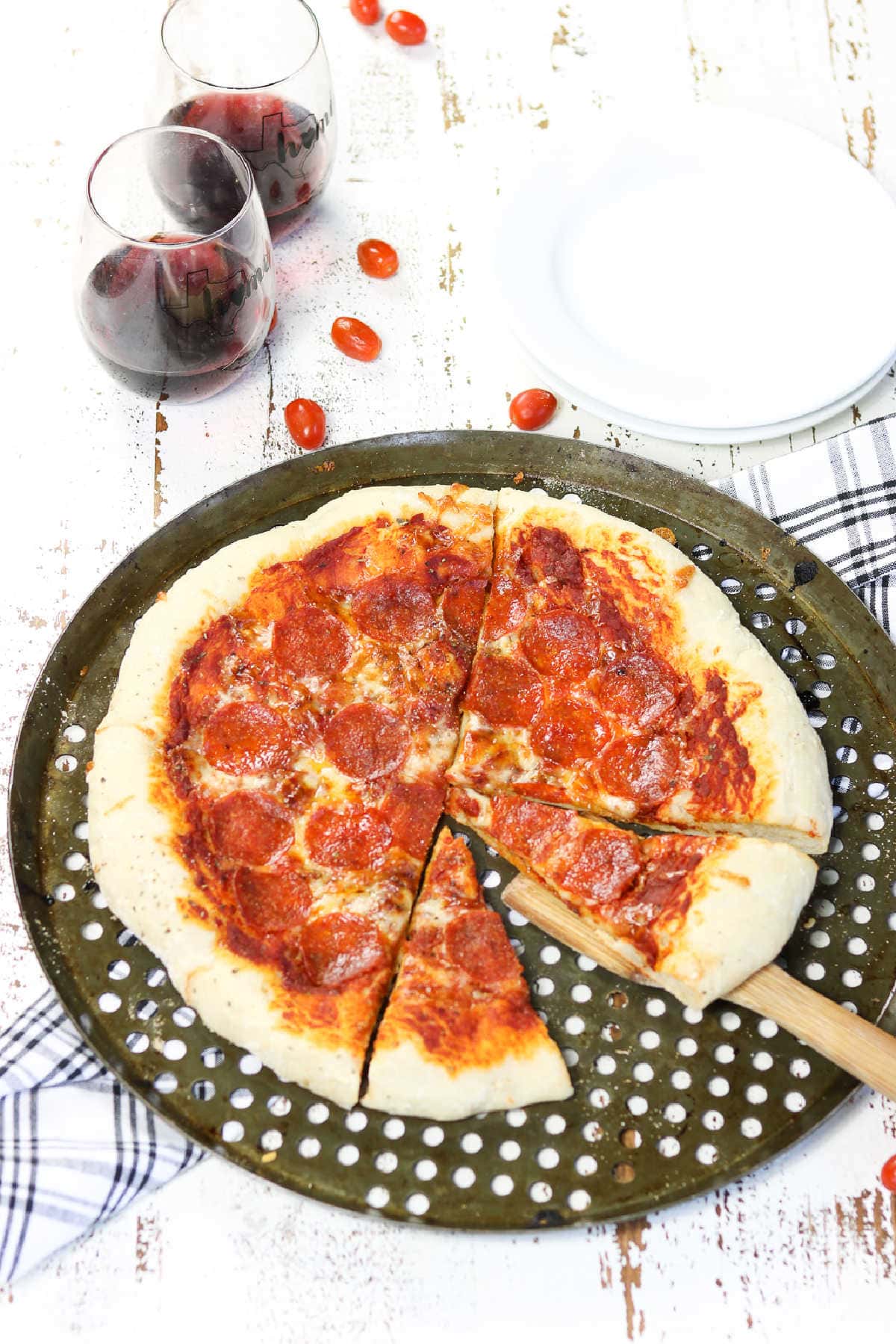 A large pizza on a pizza pan with a slice being removed.