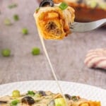 A fork picking up a bite of casserole and a long string of cheese pulling away from the plate. Title text overlay for Pinterest.