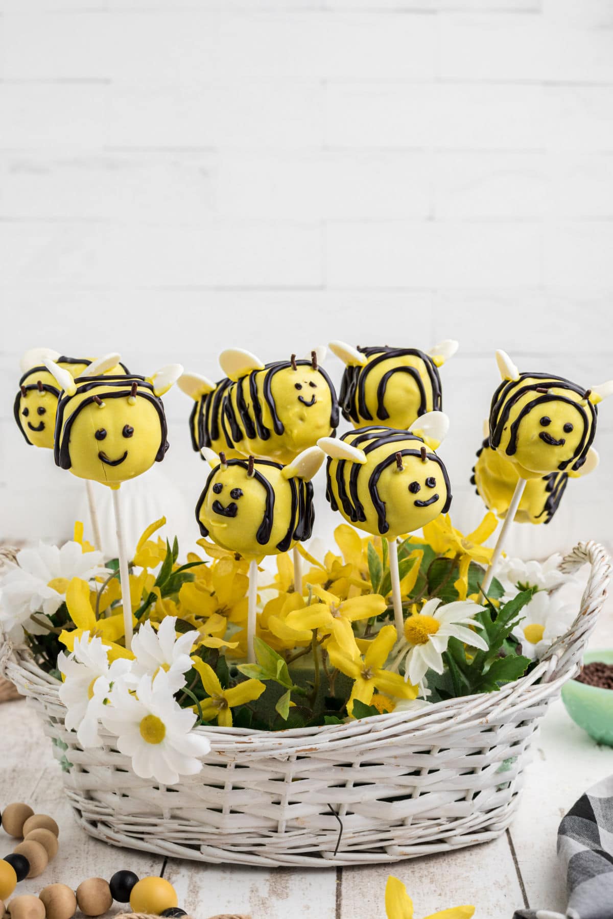 Bumble bee cake pops held upright by adding styrofoam toi a basket of flowers and pushing the sticks into it.