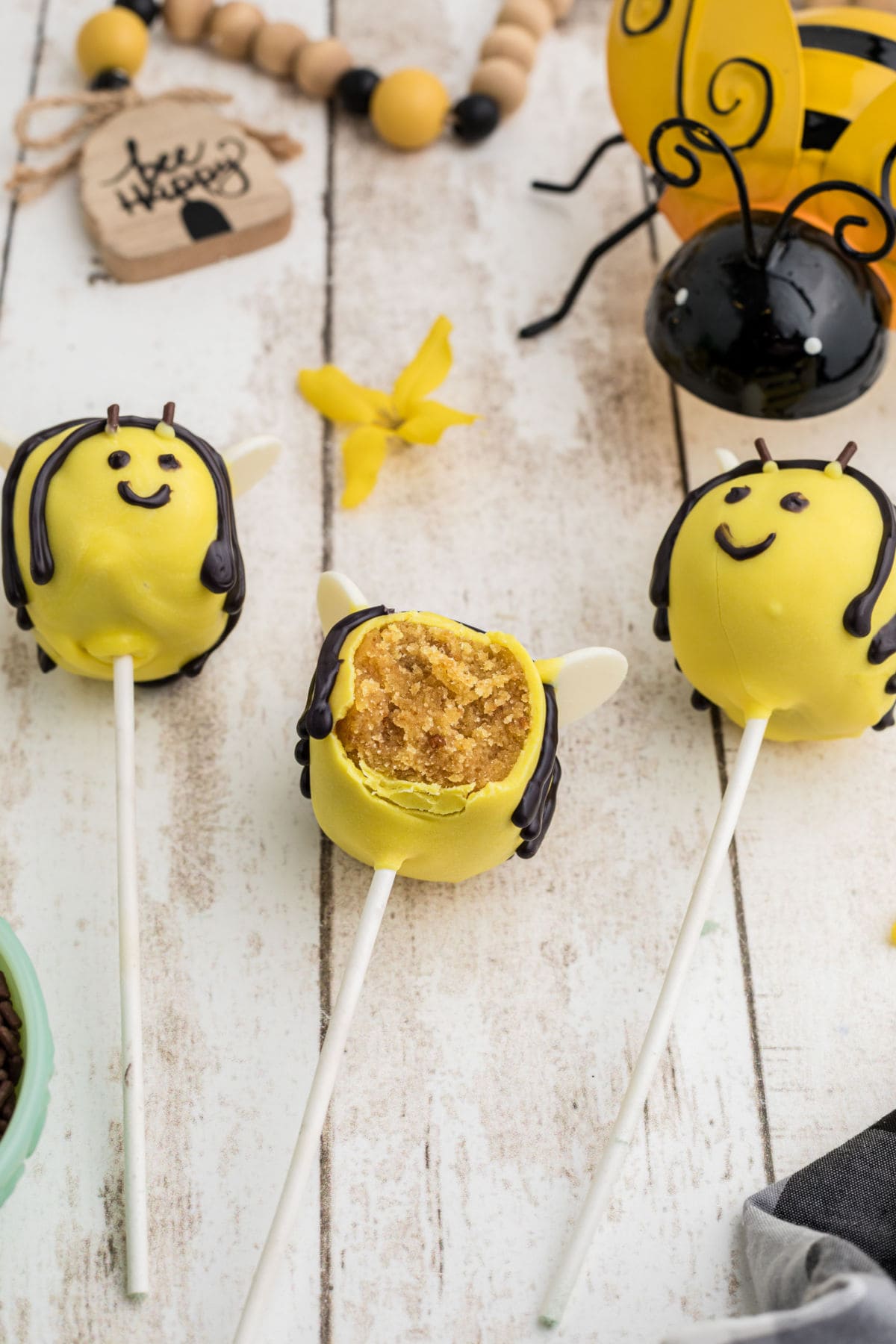 Several bumble bee cake pops on a table with a bite taken out of one.