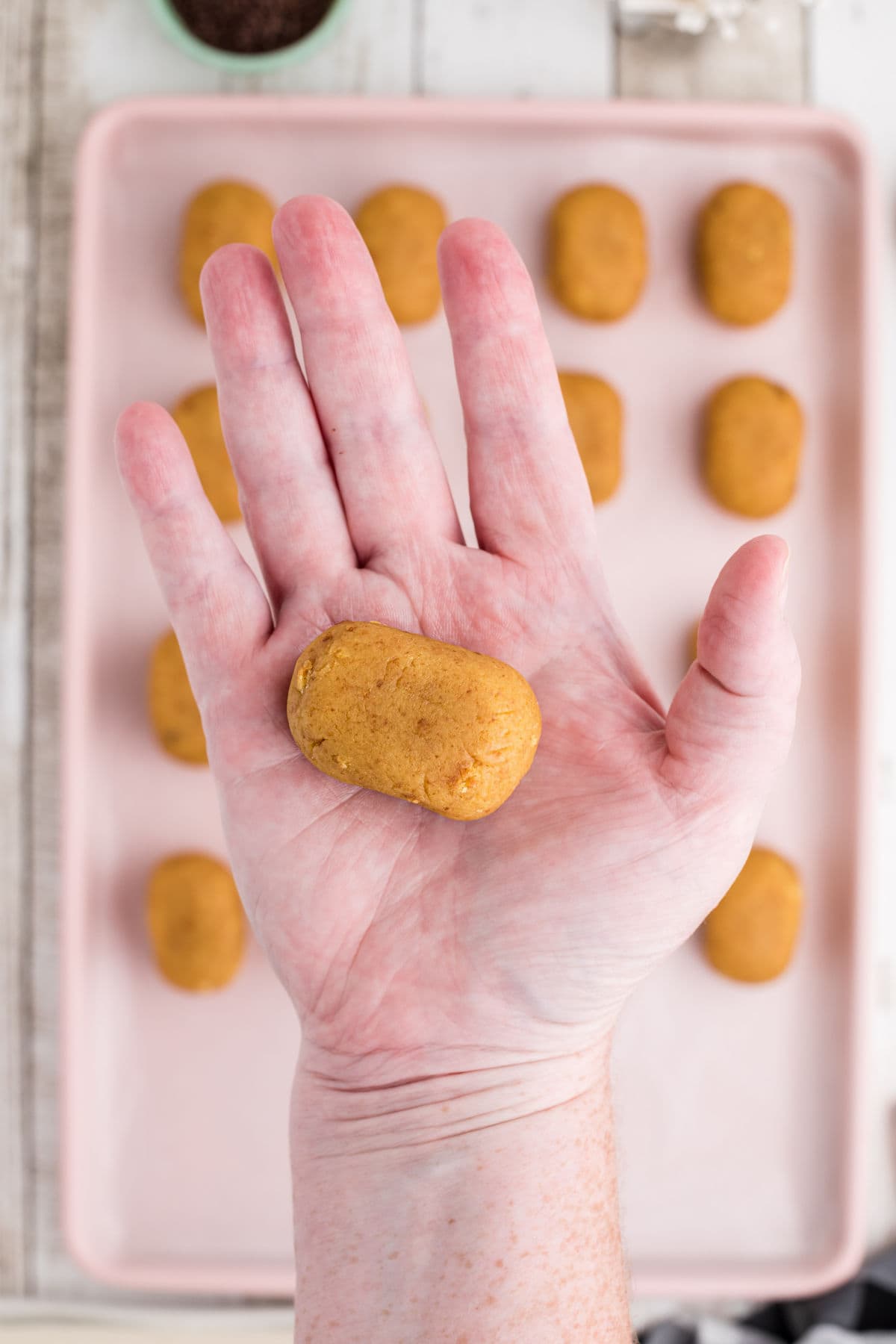 A hand with a cake ball in it showing how to form the bees body.